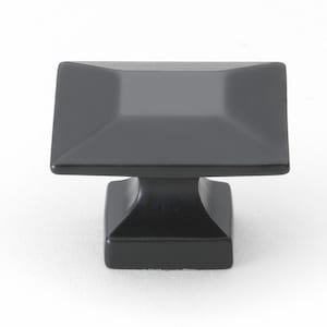 May include: Black square cabinet knob with a square base. The knob has a beveled edge and a smooth finish.