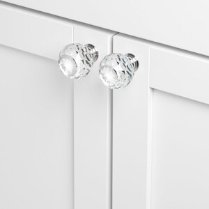 May include: Two clear crystal cabinet knobs with a faceted design and silver metal bases.