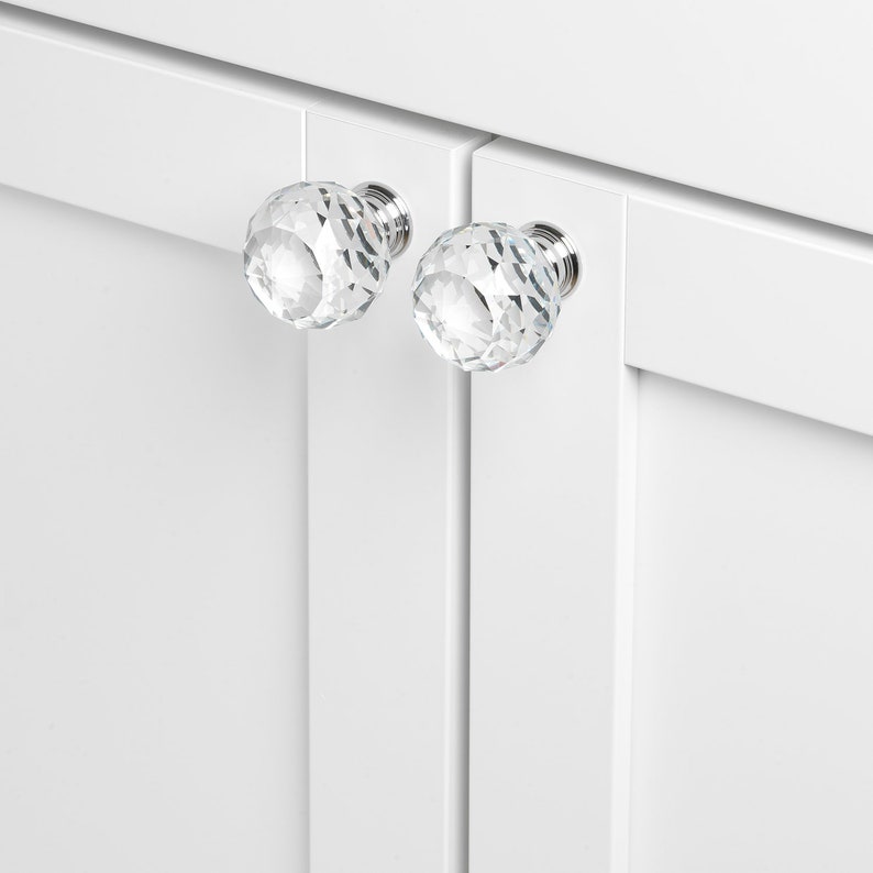 May include: Two clear crystal cabinet knobs with a faceted design and silver metal bases.