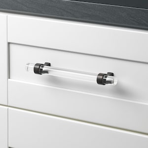 May include: A clear acrylic cabinet pull with a brushed nickel finish. The pull is approximately 5 inches long.