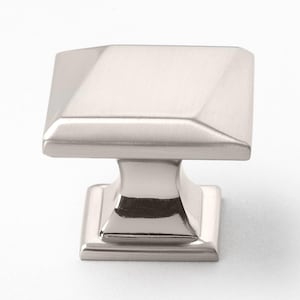 May include: A square cabinet knob with a brushed nickel finish. The knob has a square base and a raised, square top.