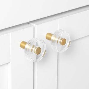 May include: Two clear acrylic cabinet knobs with a gold metal ring and a gold metal base.