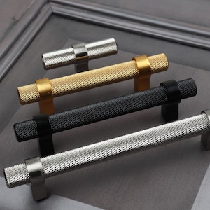 May include: Four cabinet knobs in different finishes: silver, black, gold, and nickel. Each knob has a textured, cylindrical design.