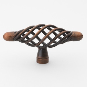 May include: A decorative cabinet knob with a twisted, cage-like design. The knob is made of metal and has a dark bronze finish.