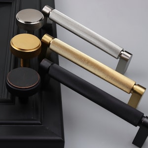 May include: Three cabinet pulls with a textured finish. The pulls are in black, gold, and silver.