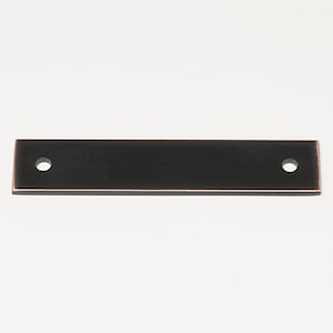 May include: A black metal drawer pull with two holes for mounting. The pull has a slightly rounded rectangular shape.