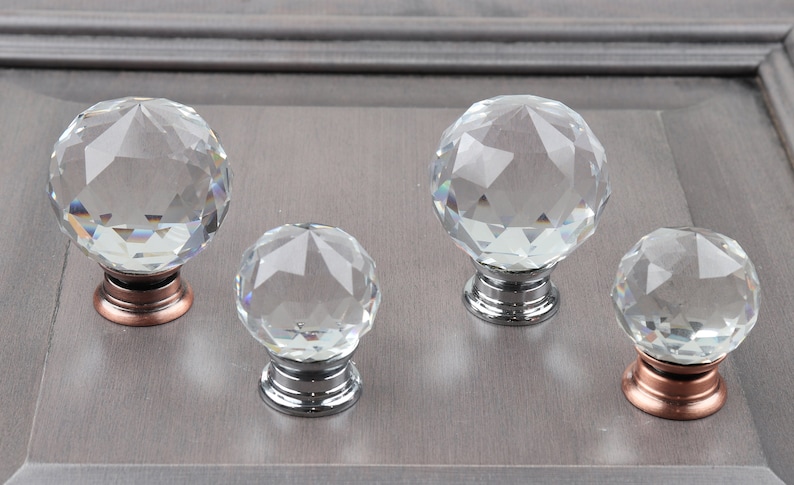 May include: Four crystal cabinet knobs with faceted surfaces. The knobs have a silver or copper base.