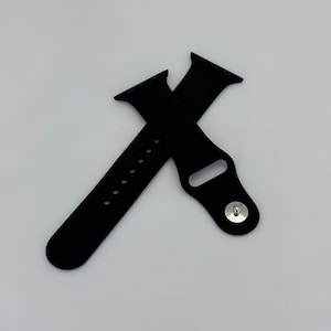 May include: Two black watch bands, one with multiple adjustment holes and the other with a silver clasp. The bands are made of a flexible material and are designed to attach to a smartwatch.