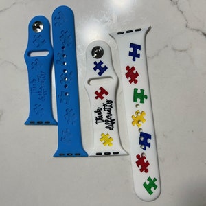May include: Four watch bands in blue and white. Two blue bands feature puzzle piece patterns and the text "Think Differently". The white bands have colorful puzzle pieces and the text "Think Differently".