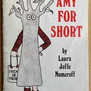 May include: A book cover with a cartoon illustration of a tree with a face and holding a trick or treat bag. The title of the book is "AMY FOR SHORT" by Laura Joffe Numeroff.