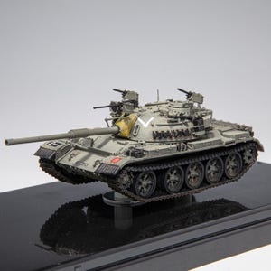 Puede incluir: Maqueta detallada de un tanque militar en tonos grises y verdes, con un largo cañón y ametralladoras. El modelo se asienta sobre una base negra, mostrando sus orugas y ruedas. El tanque presenta detalles y marcas intrincadas.