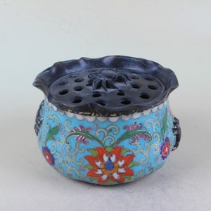 Puede incluir: Un quemador de incienso de porcelana azul y blanco con una tapa negra y diseños florales. La tapa tiene un diseño tallado y agujeros para que el incienso se queme.