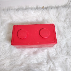 K&ouml;nnte beinhalten: Eine leuchtend rote, rechteckige Aufbewahrungsbox mit zwei runden Deckeln, auf denen jeweils das "Chitty"-Logo zu sehen ist. Der Beh&auml;lter besteht aus Kunststoff und hat einen Klappdeckel. Auf flauschigem, wei&szlig;em Hintergrund.