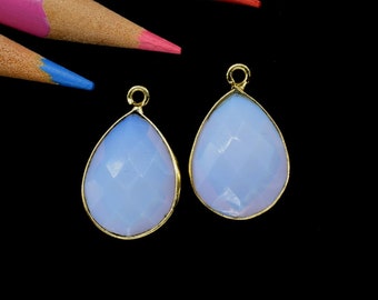 May include: Two teardrop-shaped pendants with a light blue gemstone and gold-colored metal settings.