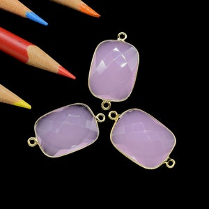 Può includere: Tre connettori in pietra preziosa rosa pallido con accenti in metallo dorato. I connettori hanno la forma di rettangoli con angoli arrotondati.