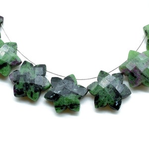 May include: A strand of green, black, and pink star-shaped gemstone beads. The beads are strung on a silver wire.