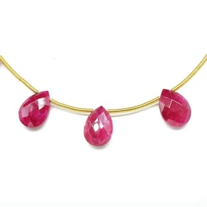 May include: A gold chain necklace with five teardrop-shaped ruby gemstones.