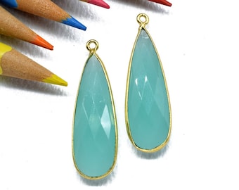 May include: Two teardrop-shaped turquoise gemstone pendants with gold-toned settings.