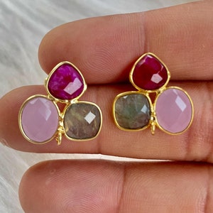 Puede incluir: Un par de pendientes de oro con tres acentos de piedras preciosas. Los pendientes presentan una piedra preciosa rosa, una verde y una roja.