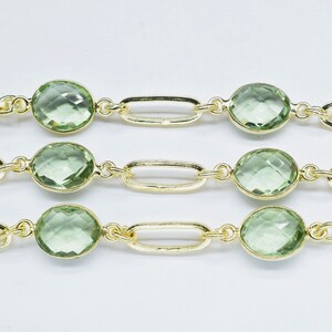 May include: A gold chain with light green oval-shaped gemstones. The chain is made of linked oval shapes.