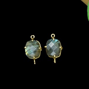 Op de afbeelding: Twee gouden metalen oorbelbevestigingen met elk een donkerblauwe labradorit edelsteen. De edelstenen zijn gefacetteerd en hebben een glinsterende, iriserende kwaliteit.