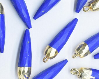 May include: A collection of 15 blue gemstone pendants with gold accents. Each pendant is shaped like a pointed teardrop and has a textured surface. The pendants are arranged on a white background.