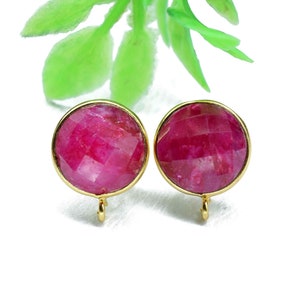 Könnte beinhalten: Ein Paar goldfarbene Ohrringe mit runden, facettierten rubinroten Steinen. Die Ohrringe haben ein schlichtes, elegantes Design.