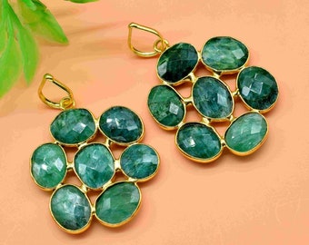 May include: A pair of gold earrings with green gemstone pendants. Each pendant features a cluster of eight oval-shaped gemstones.