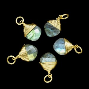 May include: Five gold-wrapped labradorite gemstone pendants with a loop for hanging. The gemstones are a light blue-green color with iridescent flashes.