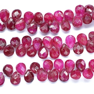 May include: A strand of faceted ruby red gemstone beads in a teardrop shape.