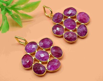 May include: A pair of gold pendant earrings with a cluster of eight faceted ruby-colored stones. The stones are set in a flower-like pattern.