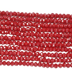 May include: A strand of red faceted glass beads. The beads are small and round, and they have a shiny finish.