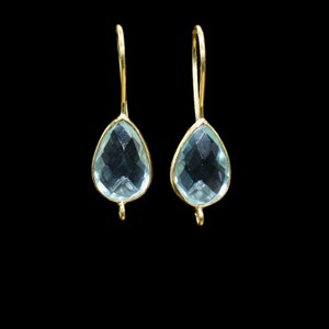 May include: A pair of gold dangle earrings with light blue teardrop-shaped gemstones.