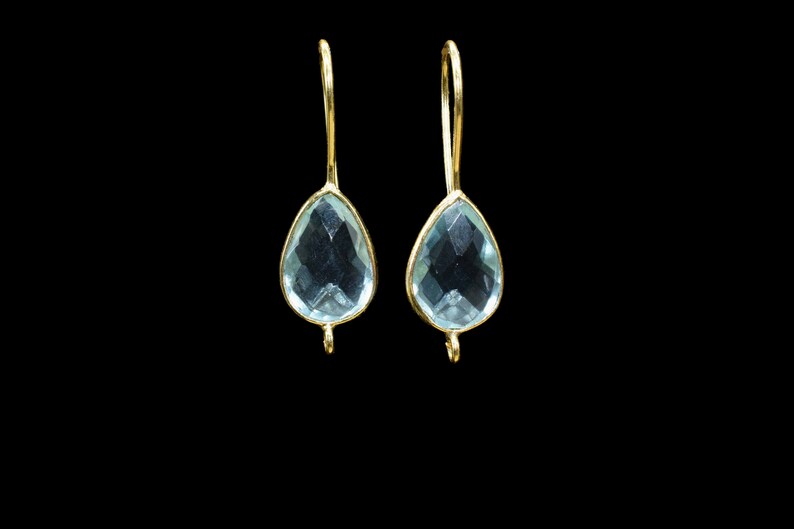 May include: A pair of gold dangle earrings with light blue teardrop-shaped gemstones.