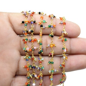 Könnte beinhalten: Eine goldene Kette mit bunten Edelsteinperlen. Die Kette besteht aus kleinen, filigranen Gliedern und verfügt über eine Vielzahl von Perlen in verschiedenen Farben, darunter Rot, Orange, Gelb, Grün, Blau und Lila.