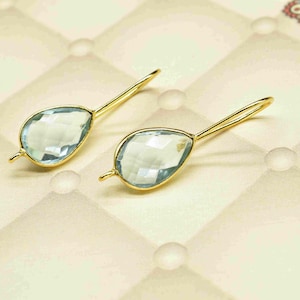 May include: A pair of gold earrings with light blue teardrop-shaped gemstones.