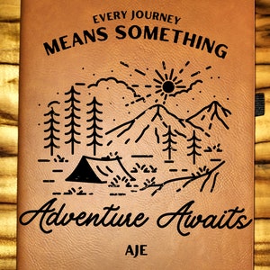May include: Brown leather journal with the text "Every Journey Means Something" and a graphic of a mountain range with a tent and trees. The text "Adventure Awaits" is below the graphic, and the name "AJE" is at the bottom.