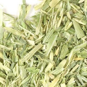 May include: Close-up of a pile of dried, light green and yellow grass clippings. The grass is finely chopped and appears to be a type of wheatgrass.