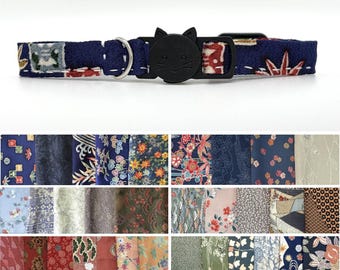 Könnte beinhalten: Ein Haustierhalsband aus Stoff mit dunkelblauer Basis und einem mehrfarbigen Blumen- und Geometriemuster, ausgestattet mit einer schwarzen Kunststoffschnalle in Katzenkopfform und einem silbernen Metall-D-Ring zur Befestigung.