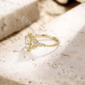 Op de afbeelding: Een gouden verlovingsring met een marquise-geslepen diamant als middensteen. De ring heeft ingewikkelde filigraan details en kleine accentdiamanten. De band is een eenvoudig, gepolijst goud. De ring staat tegen een neutrale achtergrond.