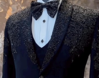 May include: A navy blue formal suit with intricate black embroidery on the lapels and shoulders. The suit includes a matching vest, a white dress shirt, and a black bow tie. The single-breasted jacket has a single button closure.