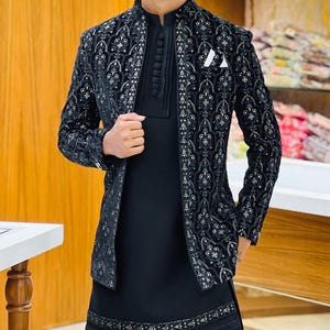 May include: Black embroidered jacket with matching black tunic and trousers. The jacket has detailed silver patterns and a mandarin collar. A white pocket square provides contrast. The outfit is suitable for formal events. The measurements are in cm.