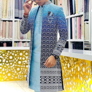 May include: A formal jacket and shirt set in shades of blue. The jacket has a gradient design, fading from light to dark blue, with detailed patterns. The shirt is a solid light blue. The outfit is suitable for formal events and occasions.