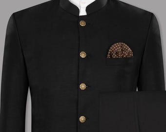 May include: A black suit with a mandarin collar, gold buttons, and a pocket square with a brown and white pattern. The suit is displayed on a mannequin. The suit includes matching black trousers.