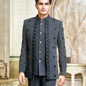 May include: A charcoal gray suit with a mandarin collar, featuring intricate black floral embroidery. The jacket has a button-up front and is paired with matching trousers. The suit is a formal wear ensemble.