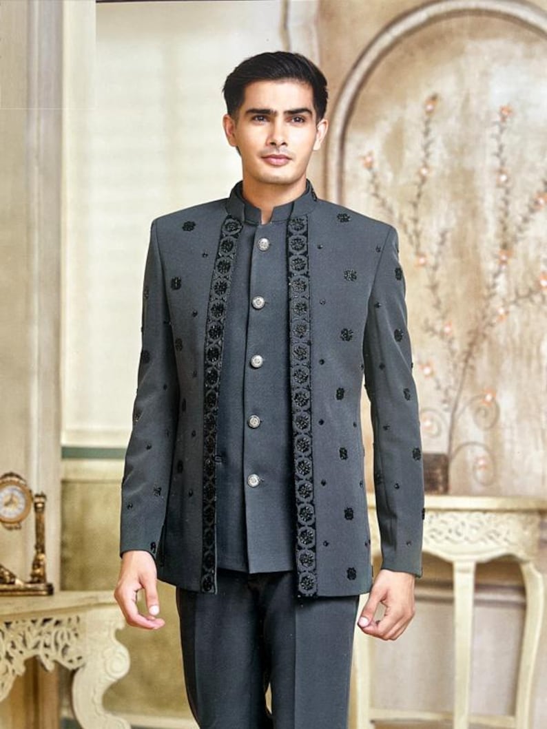 May include: A charcoal gray suit with a mandarin collar, featuring intricate black floral embroidery. The jacket has a button-up front and is paired with matching trousers. The suit is a formal wear ensemble.