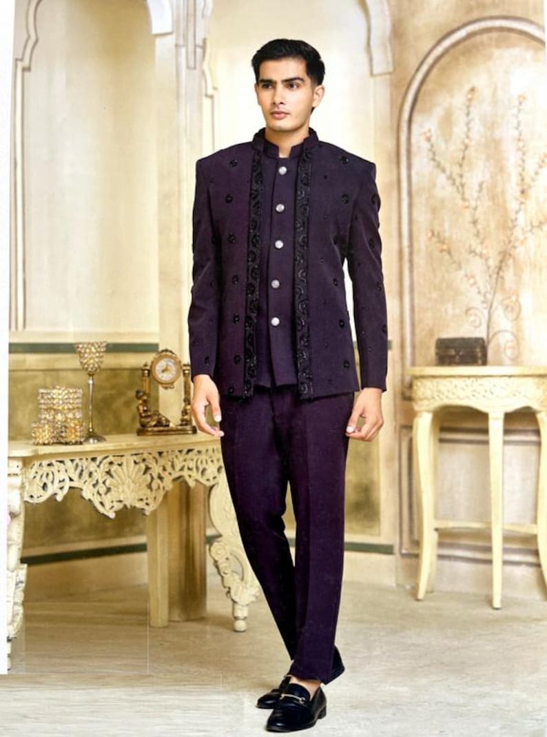May include: A dark purple suit with a mandarin collar jacket and matching pants. The jacket features black embroidered detailing and a row of white buttons. The outfit is completed with black dress shoes, creating a formal and elegant ensemble.