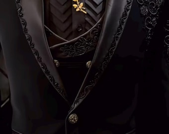 Puede incluir: Un traje negro formal con detalles intrincados. El traje presenta una pajarita negra, un chaleco con botones decorativos y un broche de rosa dorada. La chaqueta tiene bordados ornamentados en las solapas y hombros.