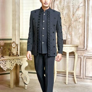 May include: A charcoal gray suit with a mandarin collar, featuring intricate black floral embroidery. The suit includes a matching vest and trousers. The ensemble is completed with black loafers. The background has a vintage aesthetic.
