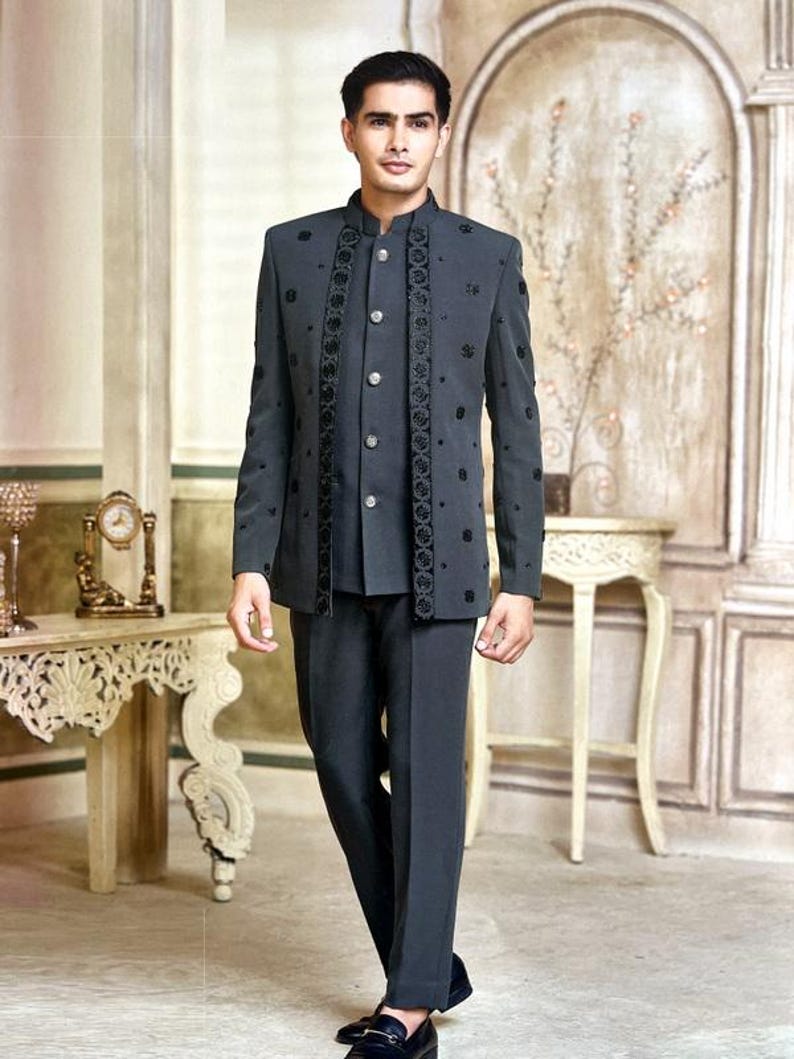 May include: A charcoal gray suit with a mandarin collar, featuring intricate black floral embroidery. The suit includes a matching vest and trousers. The ensemble is completed with black loafers. The background has a vintage aesthetic.